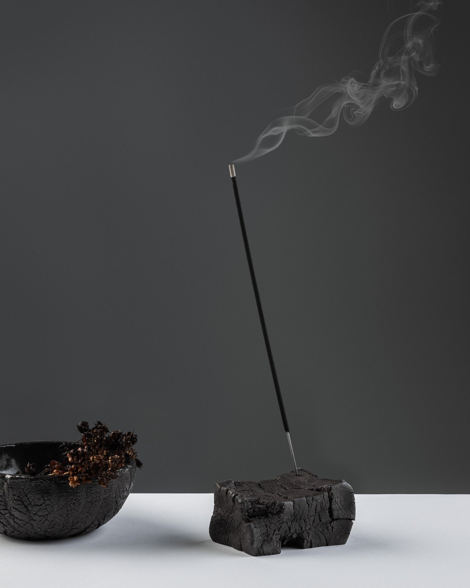 Black stoneware incense holder in a brick-like form.