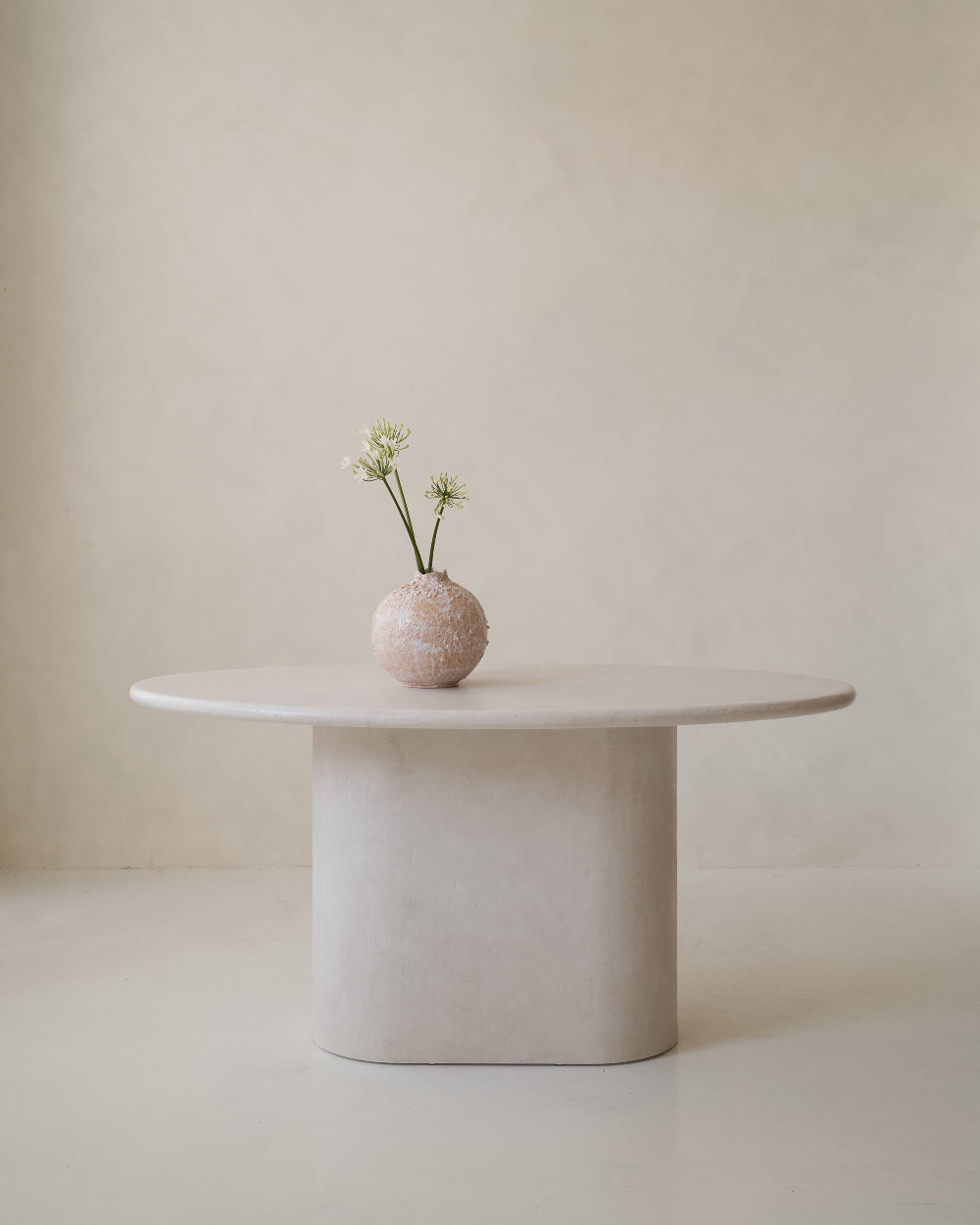 Close-up of Kanso Ellipse microcement dining table with decorative vase