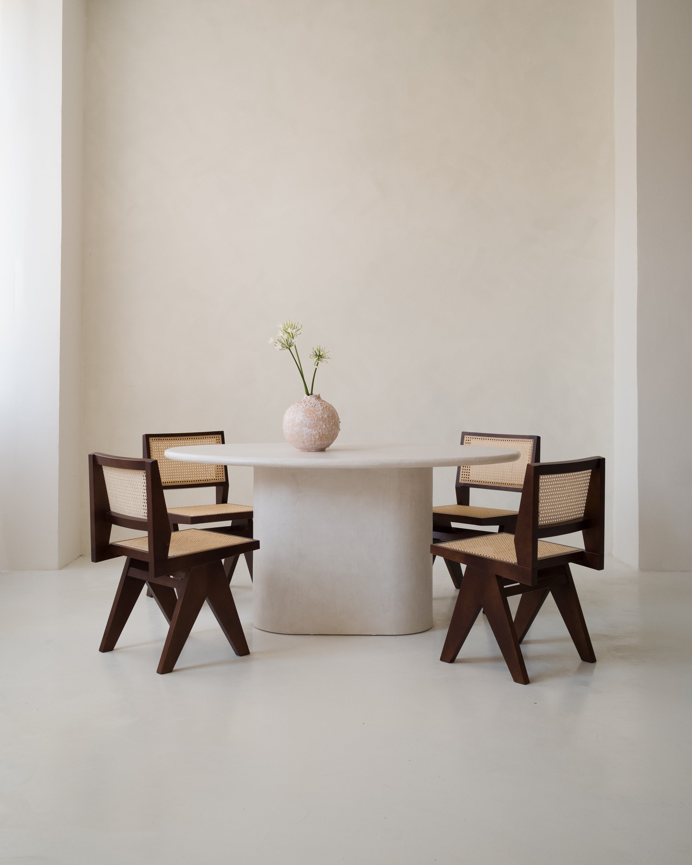 Kanso Ellipse microcement dining table styled with wooden chairs in minimalist interior