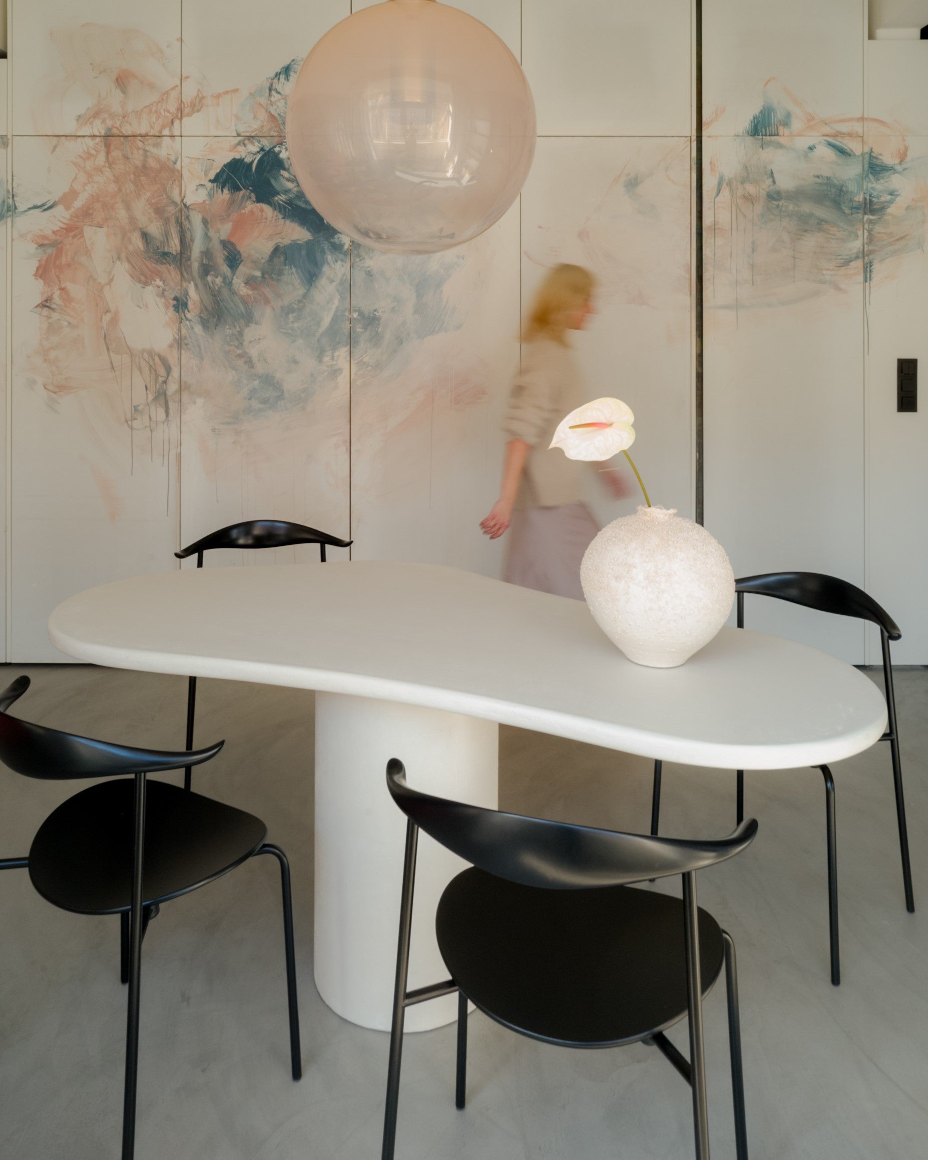 Kanso Organic microcement dining table styled with black chairs and pendant lamp