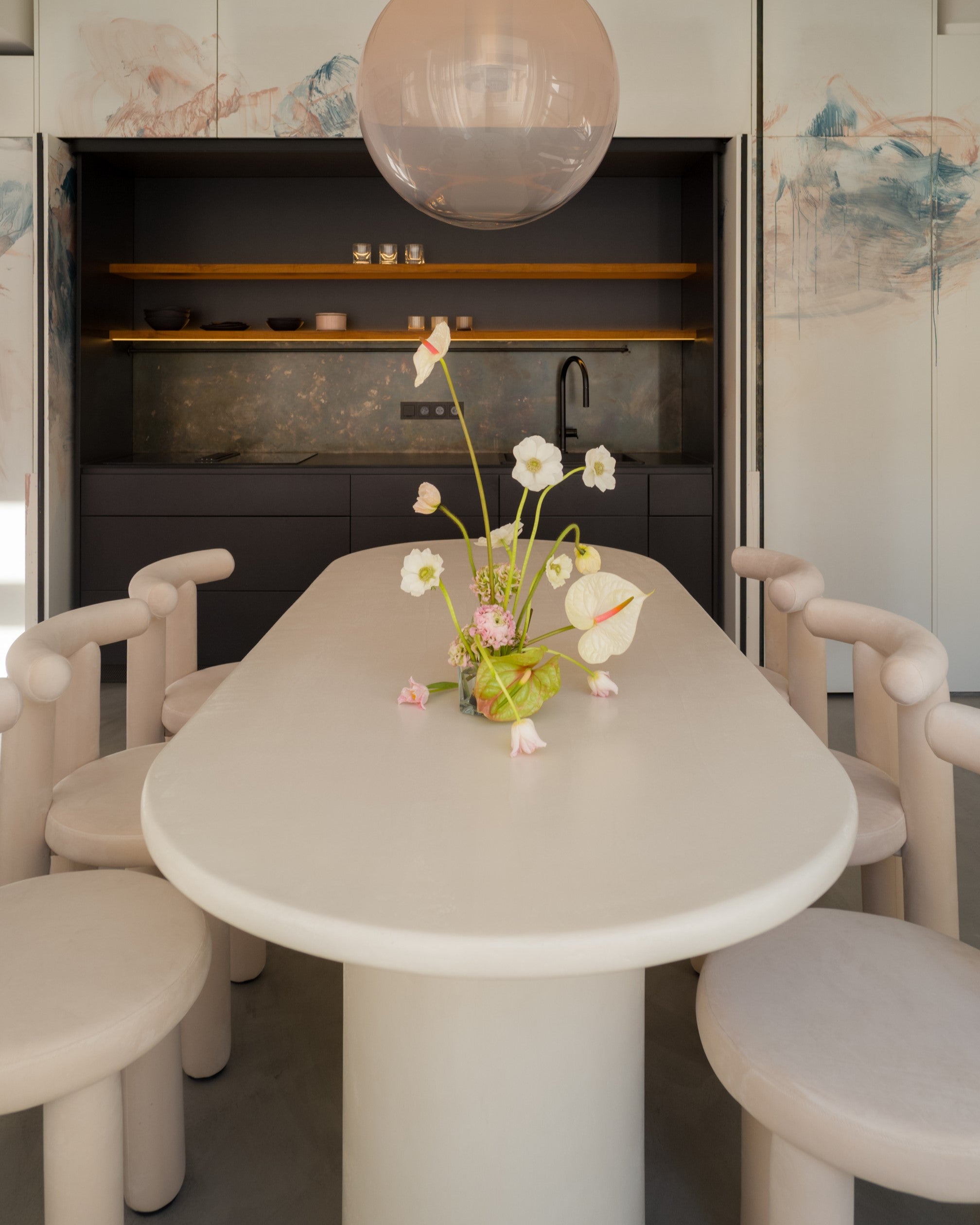 Close-up of Kanso Oval microcement dining table surface styled with ceramics