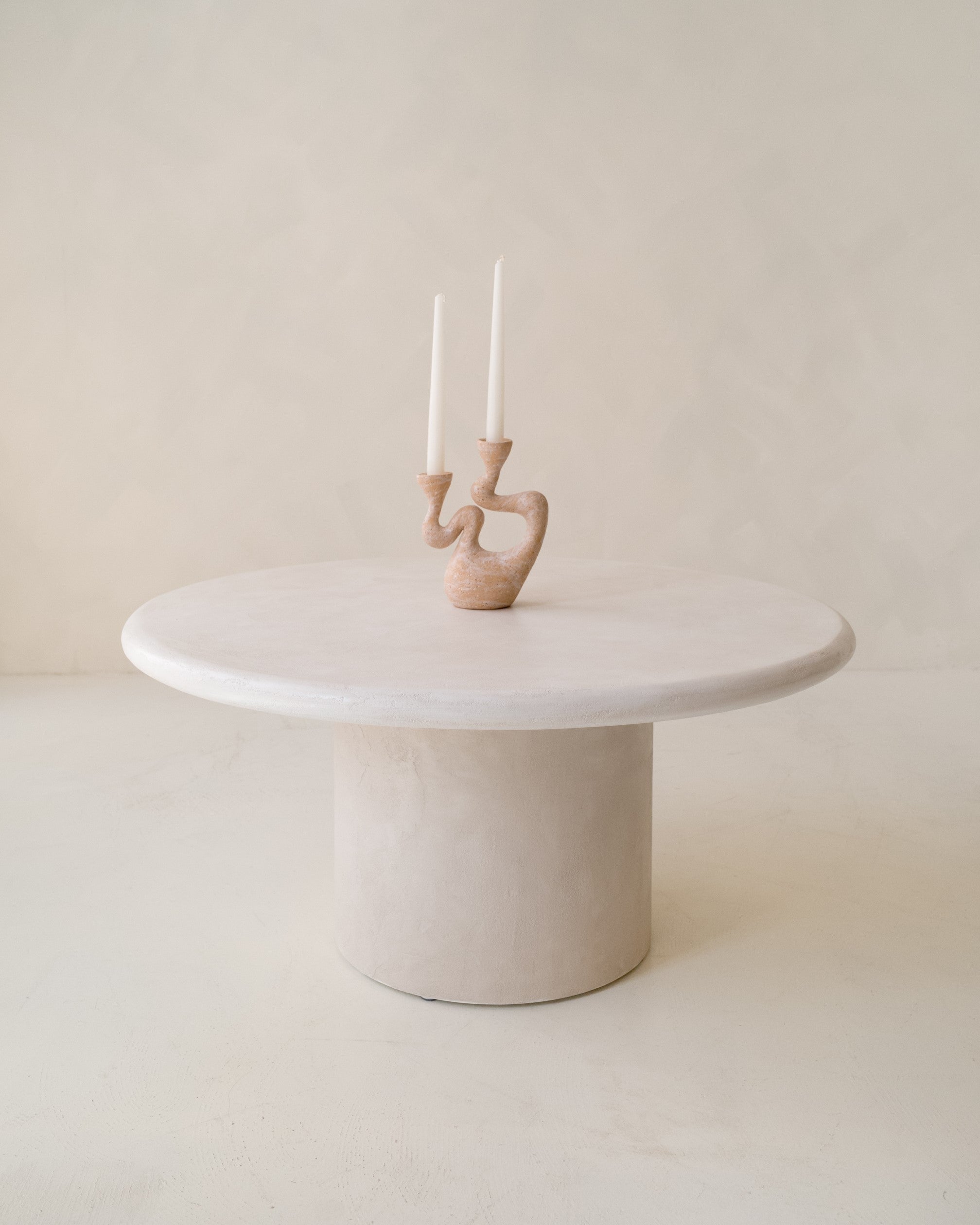 Minimalist styling of Kanso round microcement coffee table with decorative vase