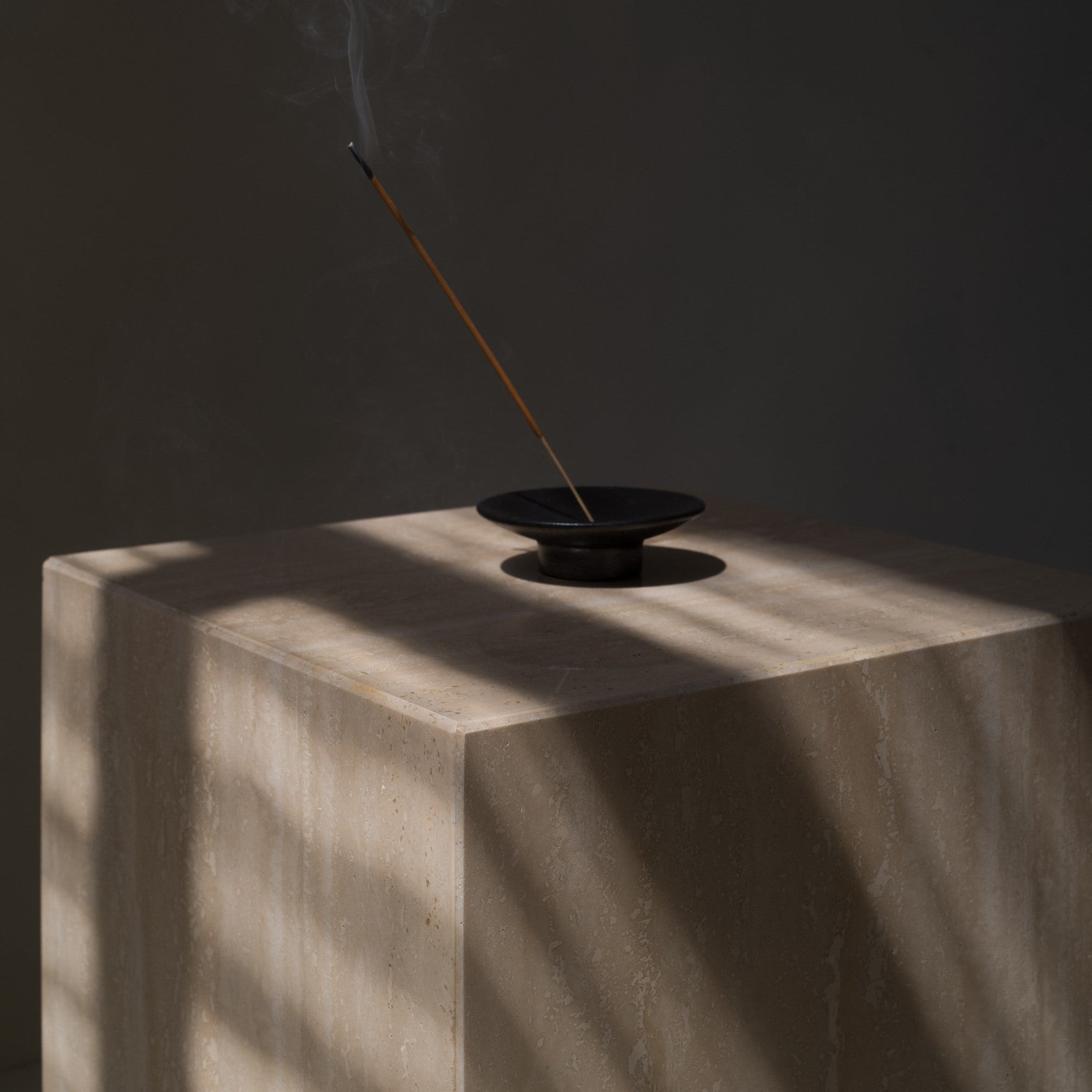 Close-up of travertine side table in dark setting, polished stone surface