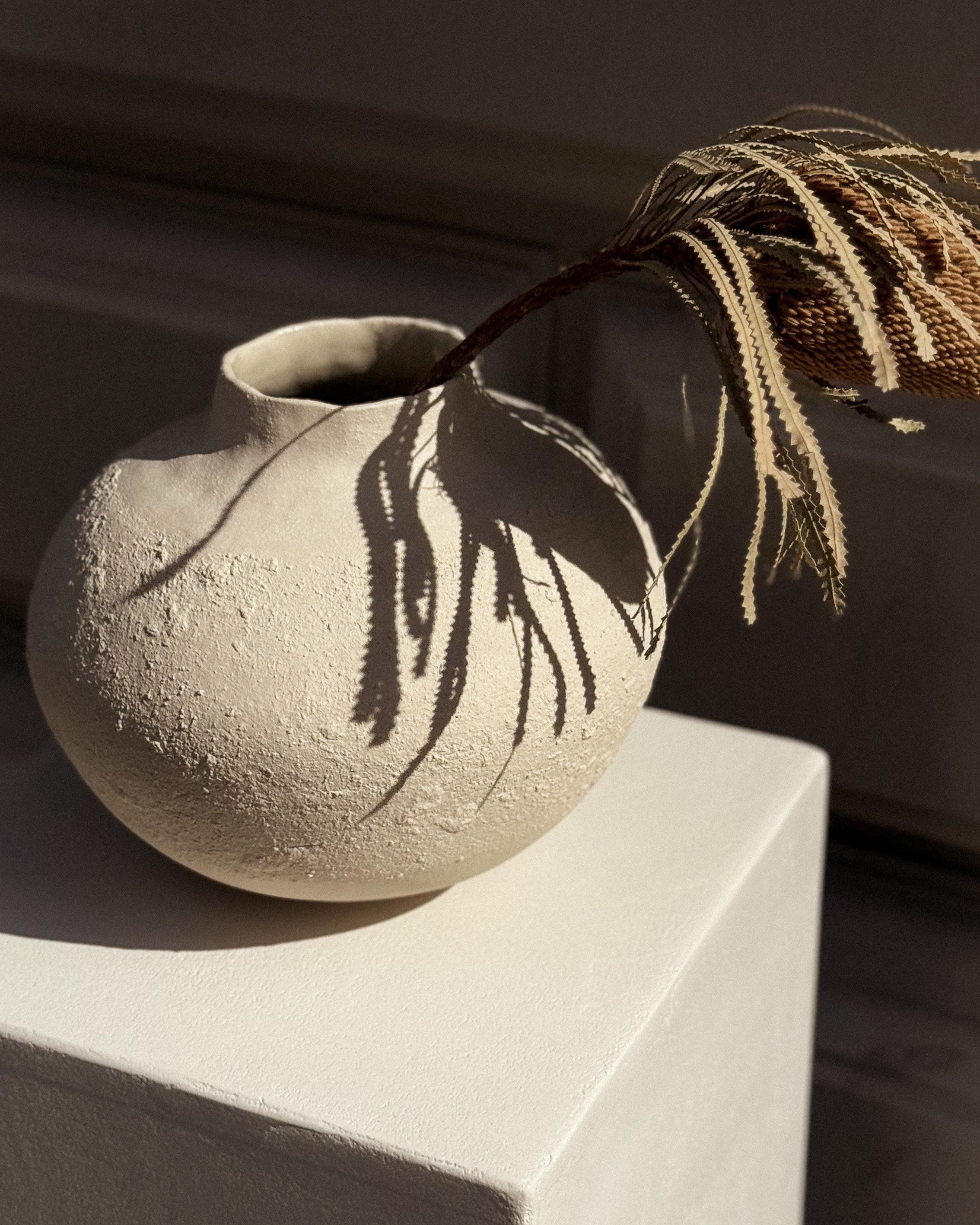 Unique ceramic vase in warm light, highlighting its natural texture and organic silhouette.