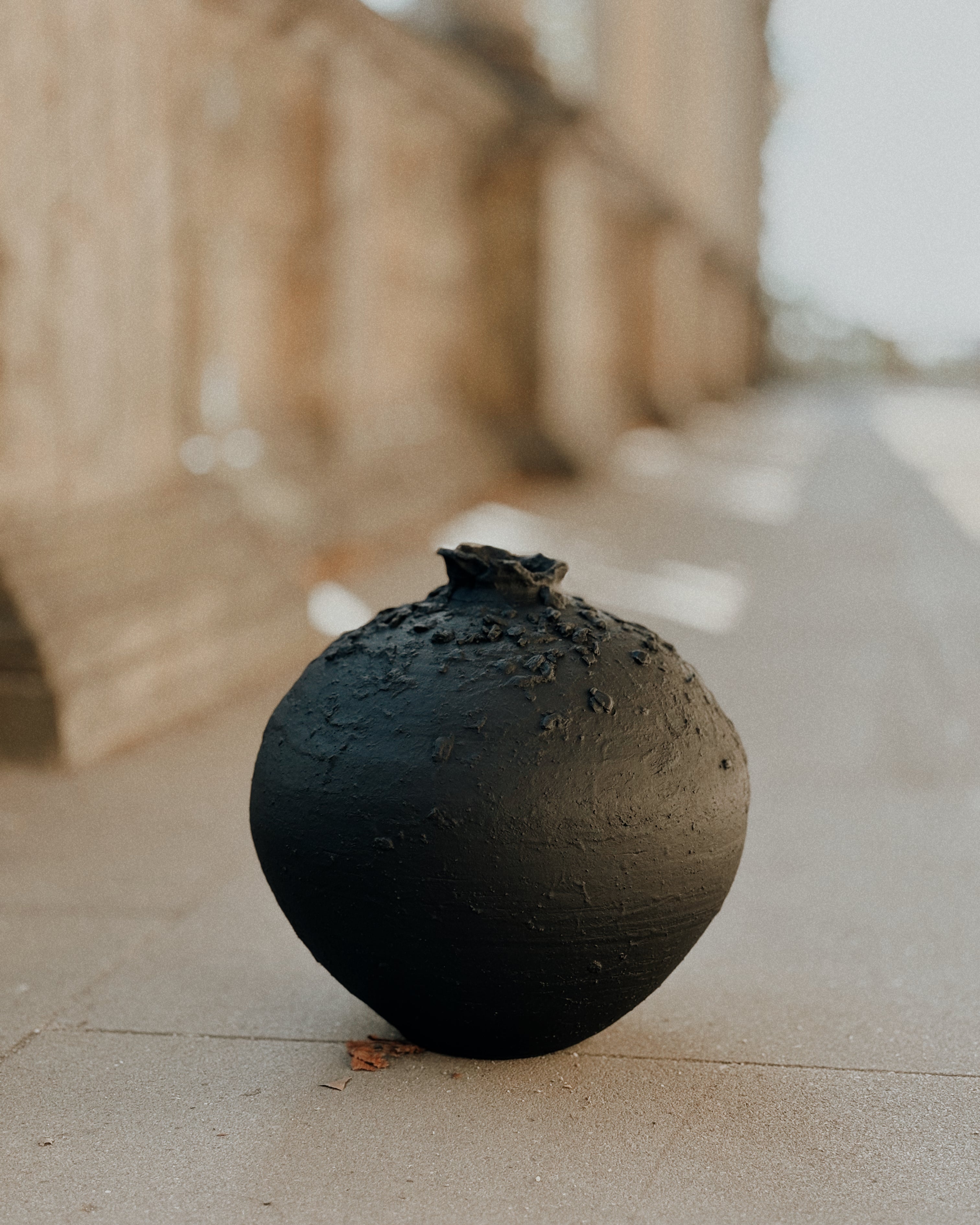 Handmade black ceramic Sabi vase placed outdoors, showing textured organic surface