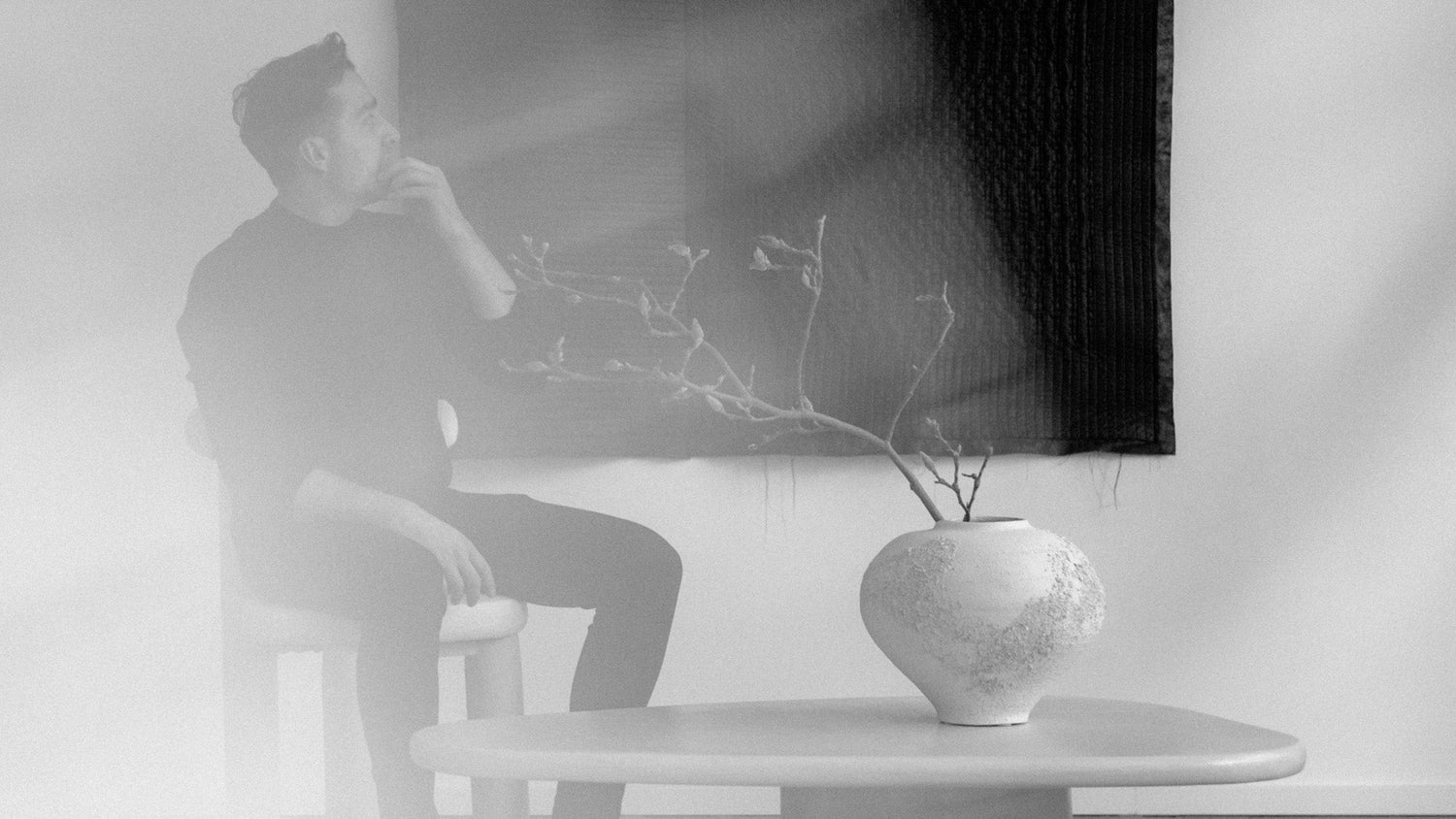 Minimalist black and white interior featuring a handcrafted Syneste vase with organic branches, capturing calm, texture, and timeless design.