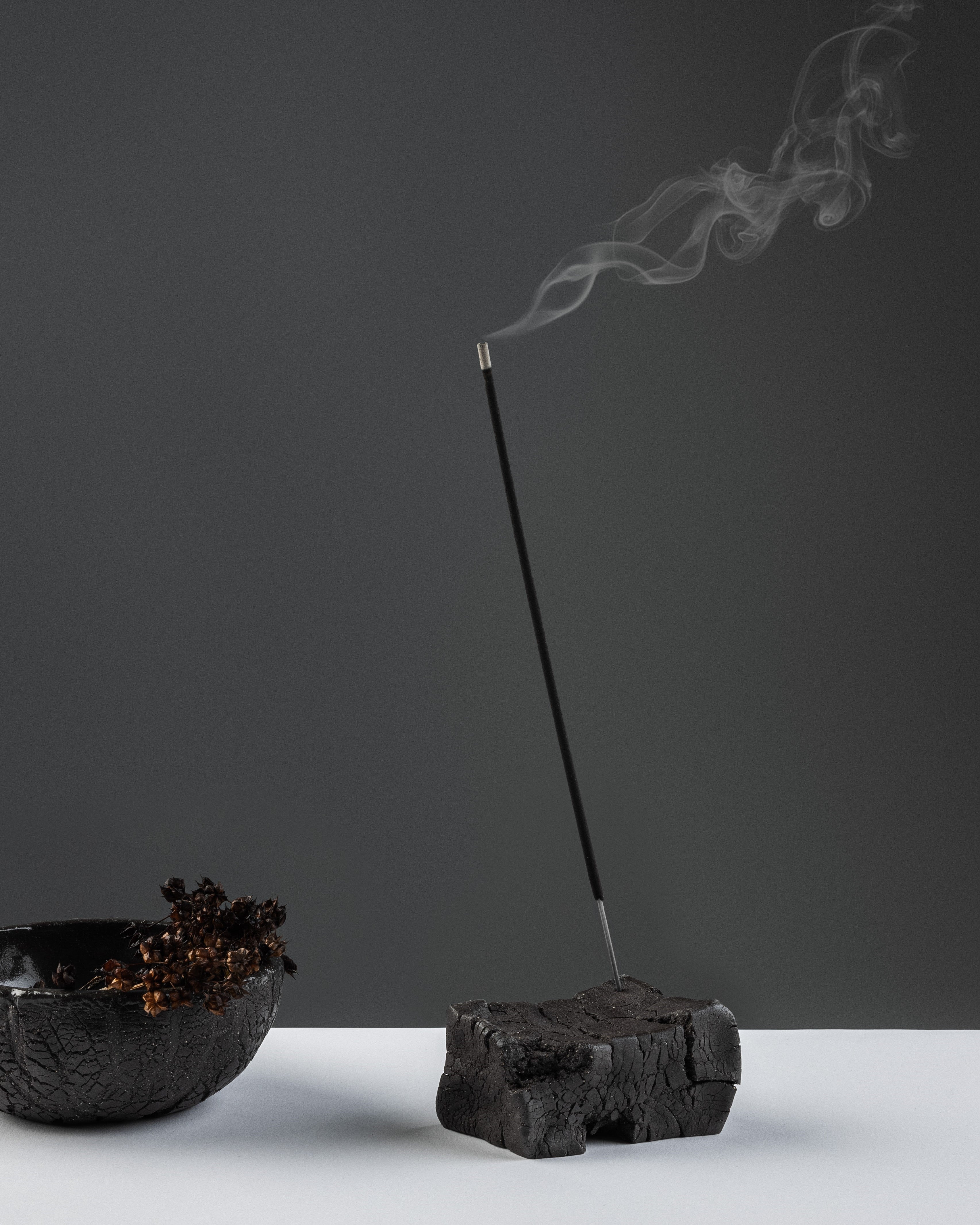 Black stoneware incense holder in a brick-like form.