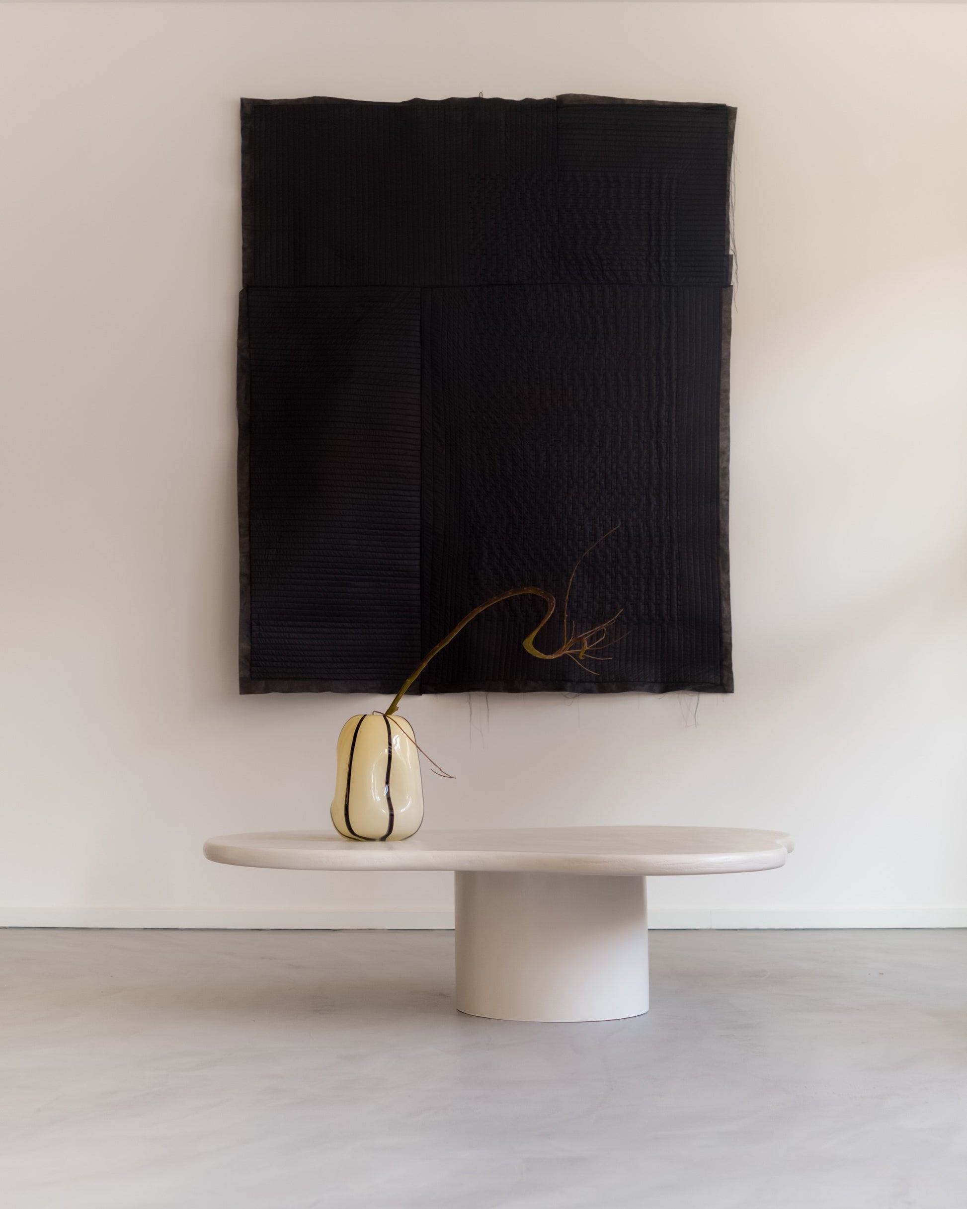 Minimalist styling of Kanso Organic microcement coffee table against wall with textile art