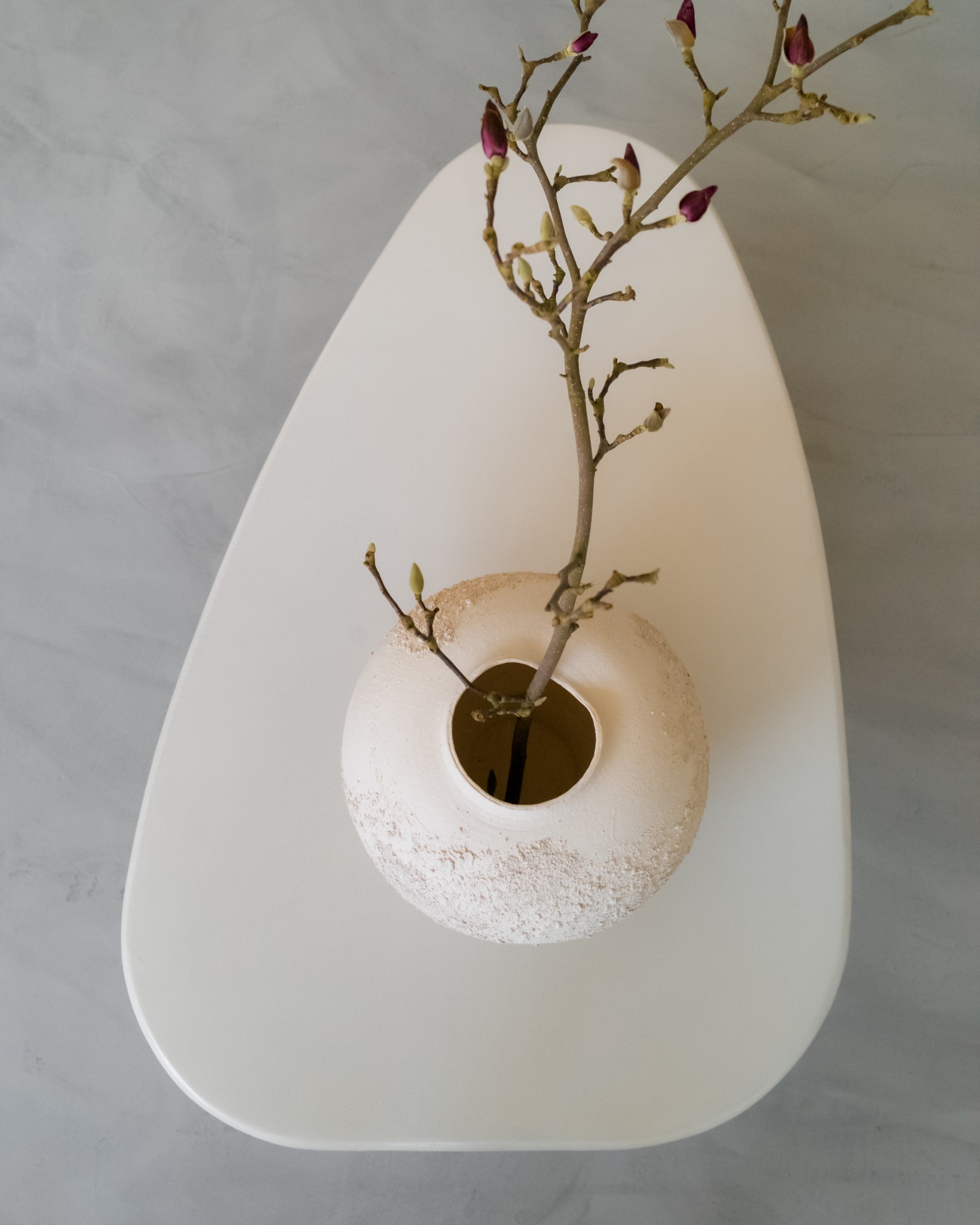 Close-up of Kanso Wing microcement coffee table with small vase