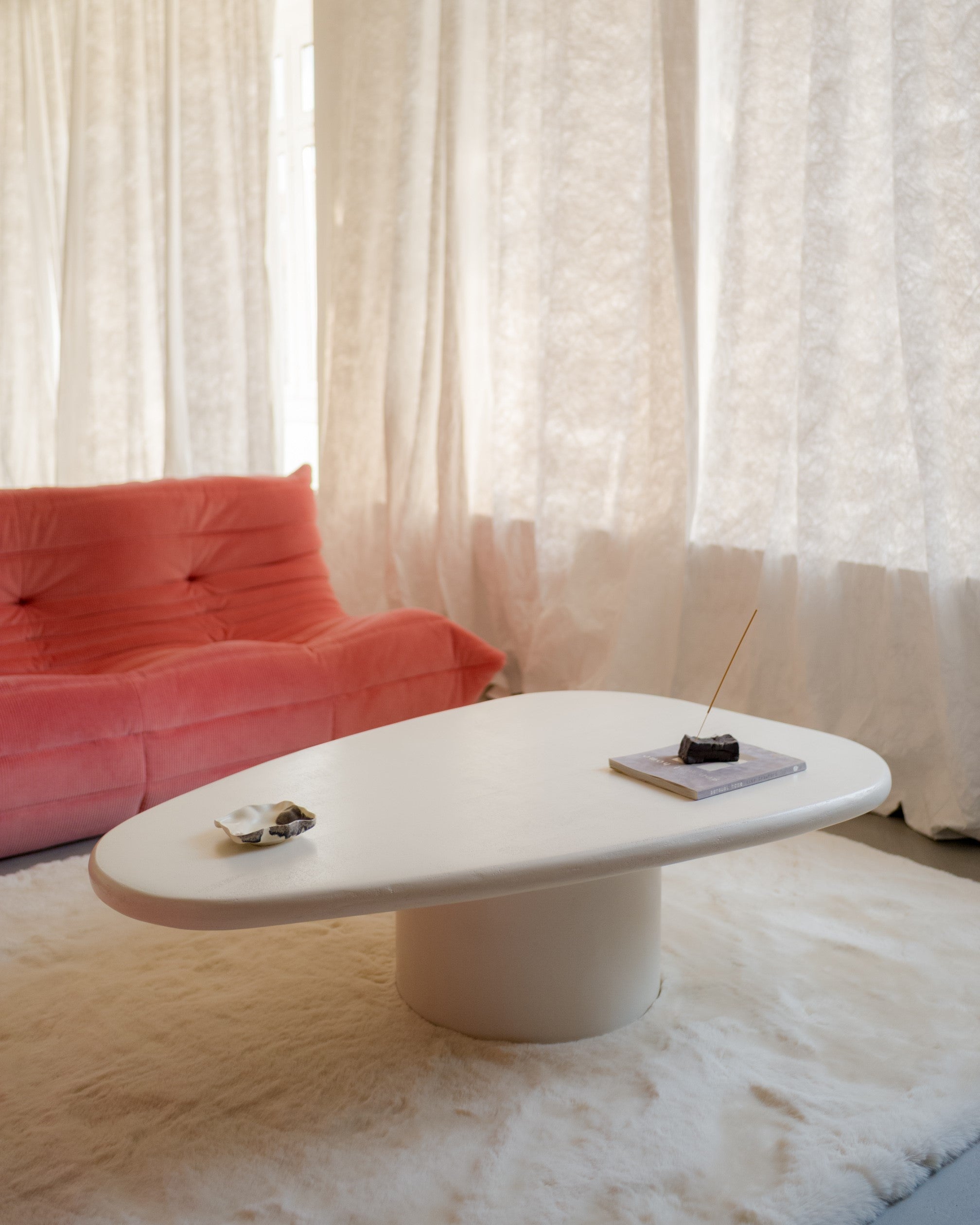 Kanso Wing coffee table in microcement placed in living room with pink sofa