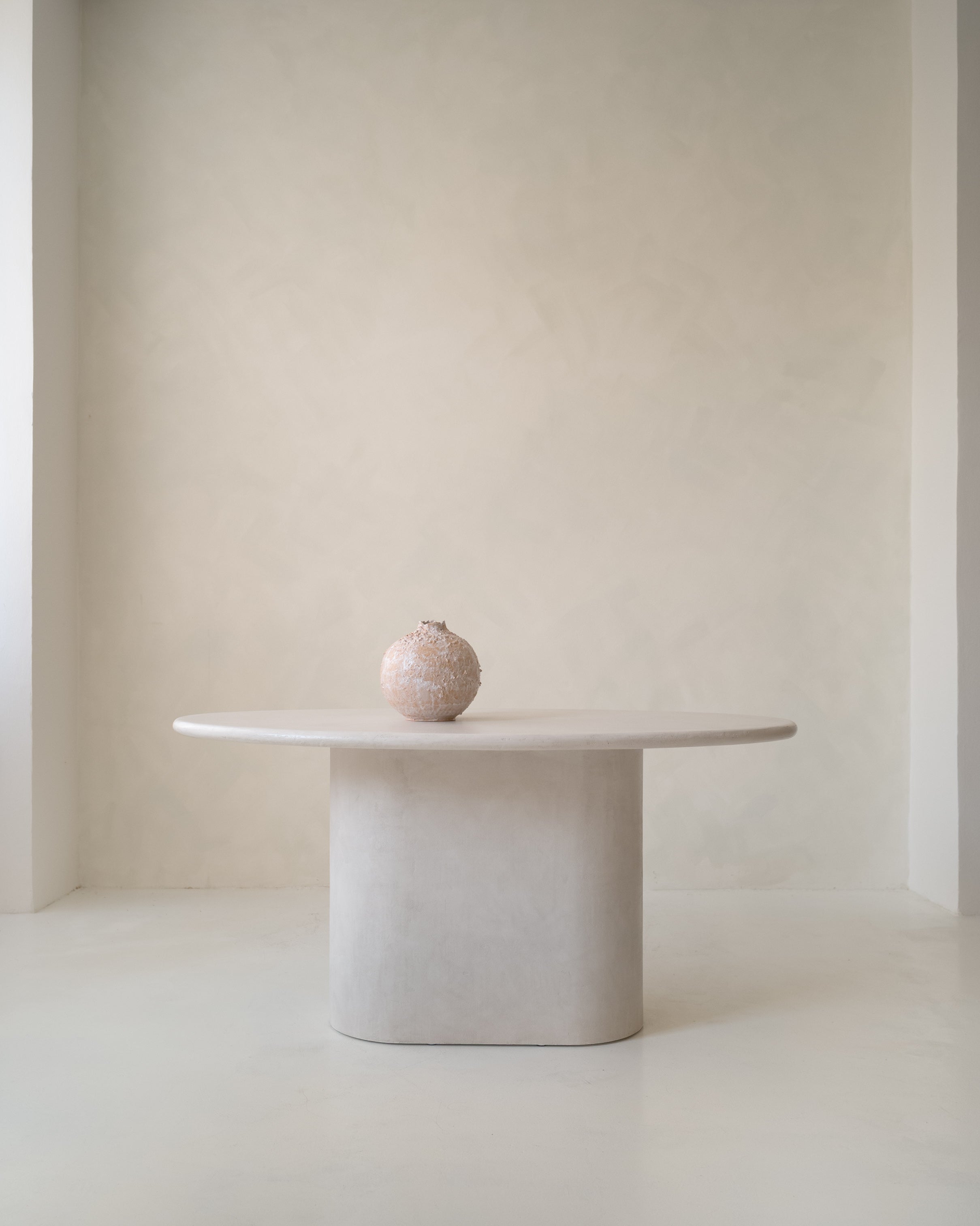 Side view of Kanso Ellipse dining table showing sculptural microcement base