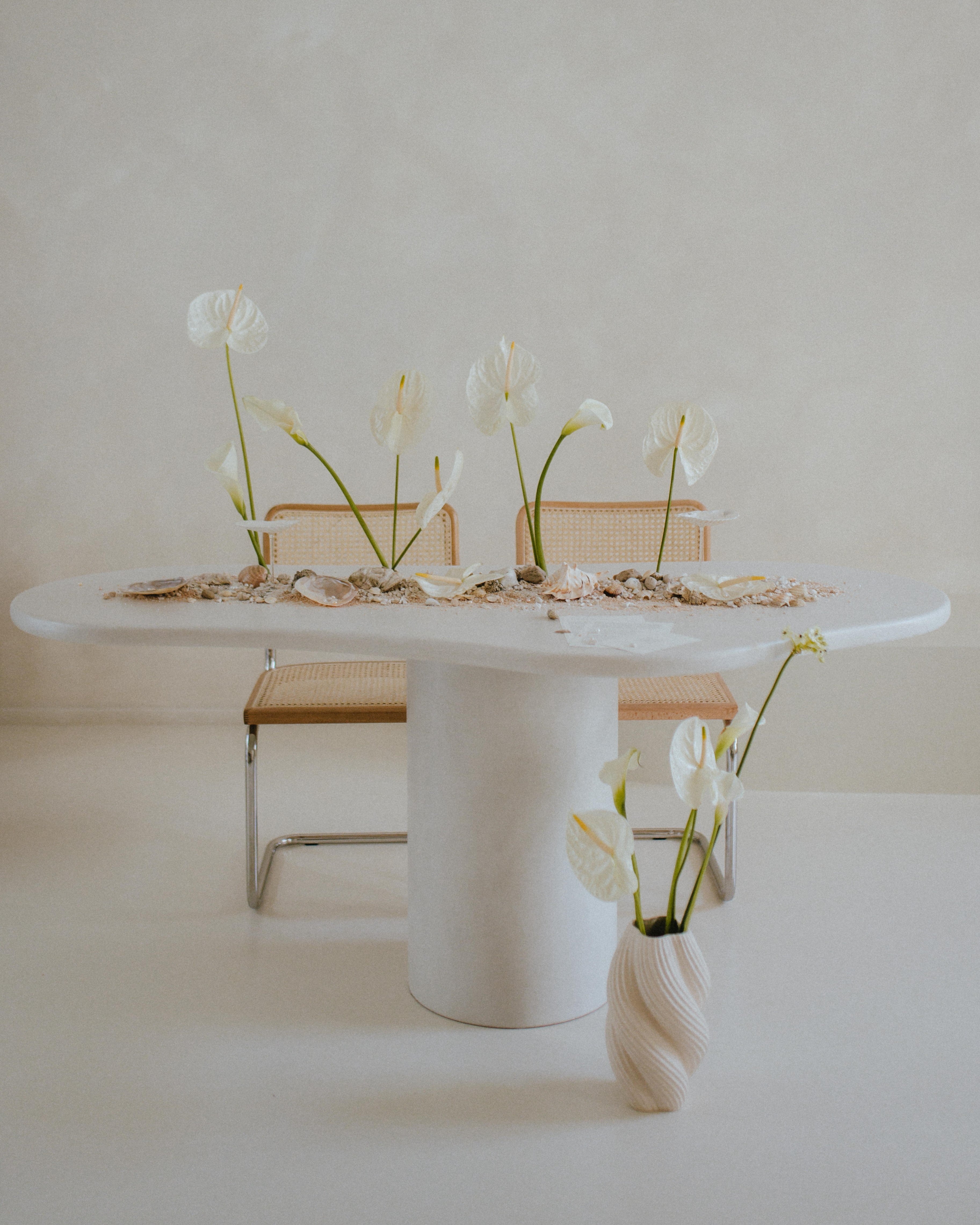 Kanso Organic microcement dining table styled with flowers and chairs in a bright room