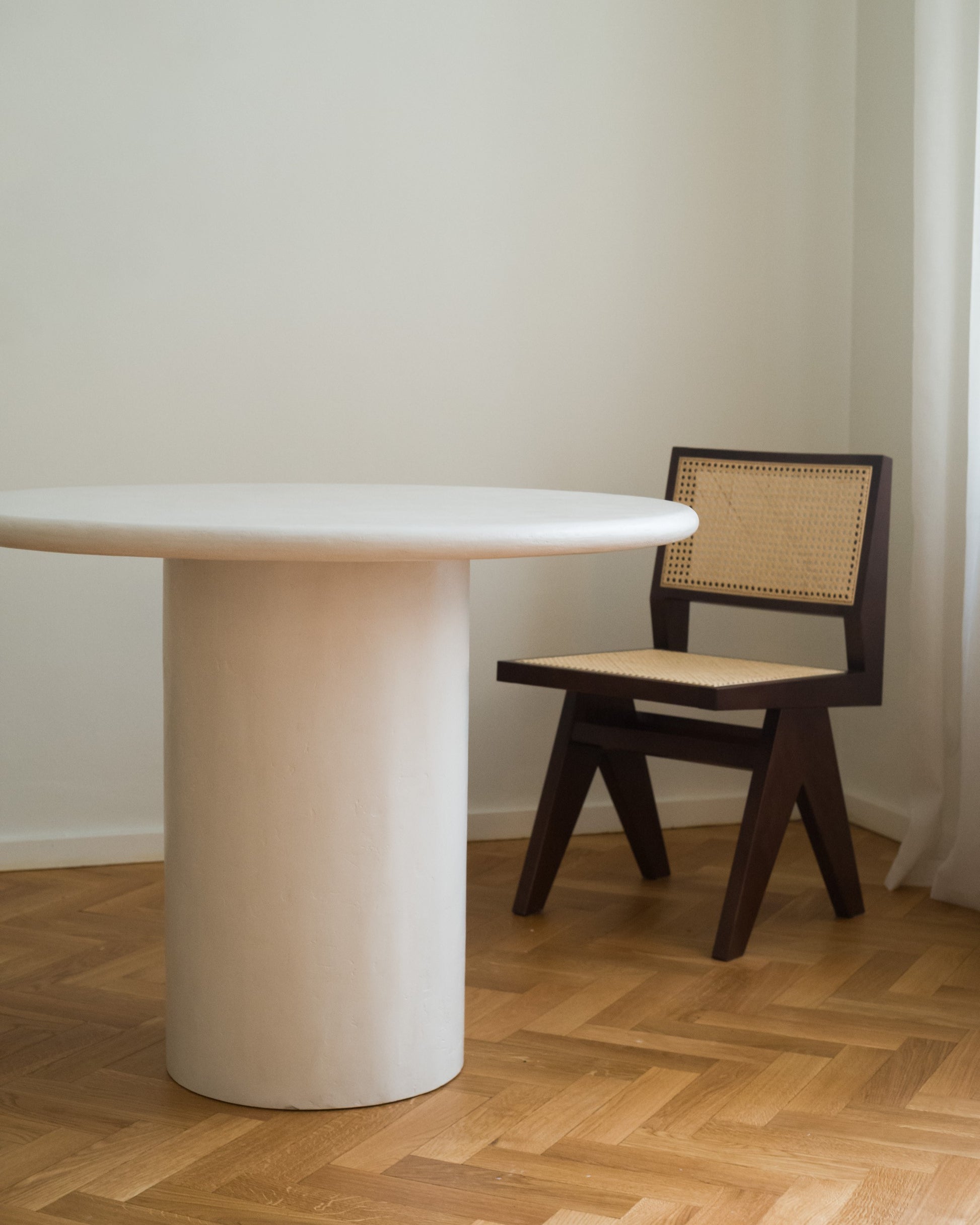 White Kanso Round dining table placed in bright interior with wooden floor