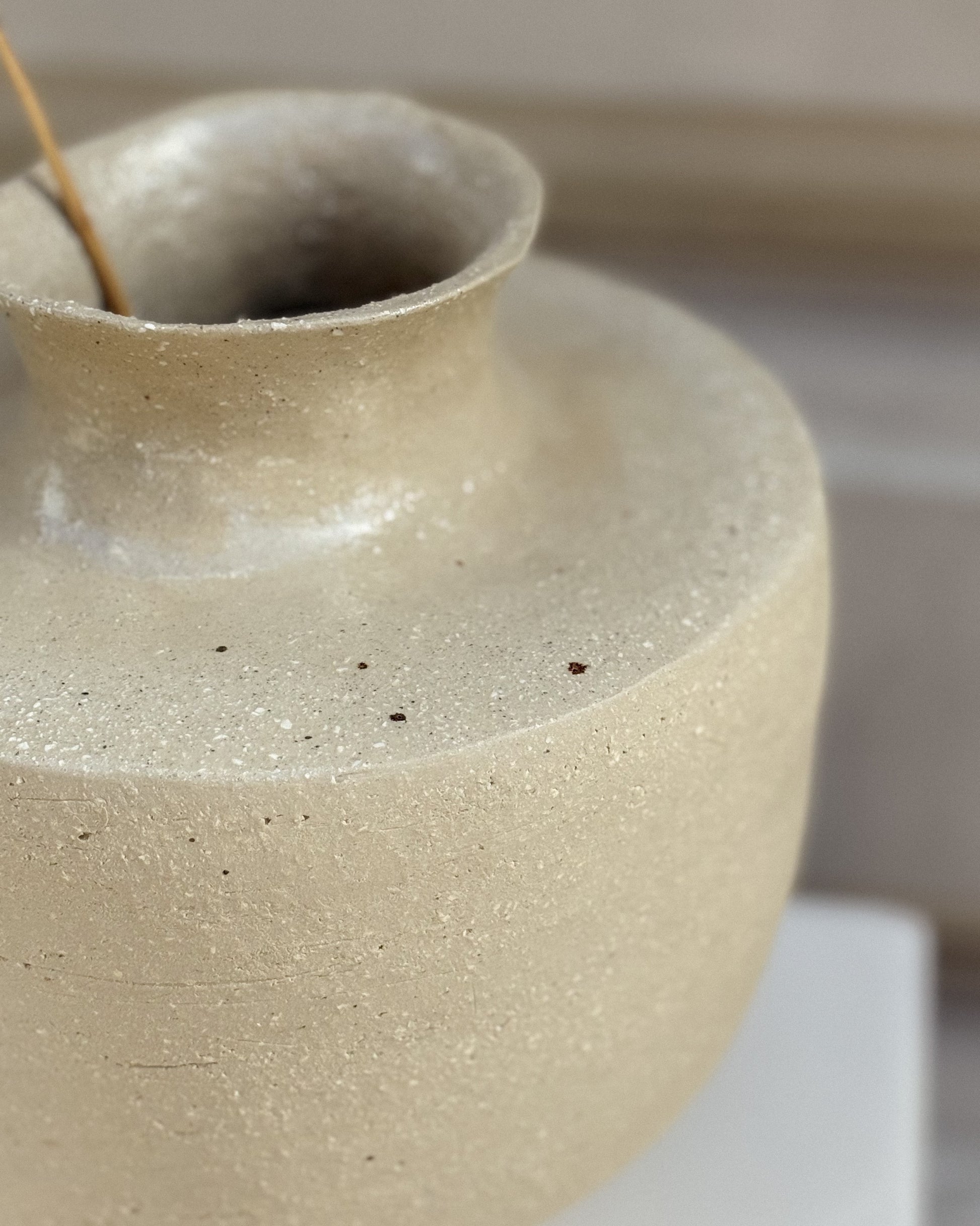 Handcrafted detail – stoneware vase with fine texture and narrow neck.